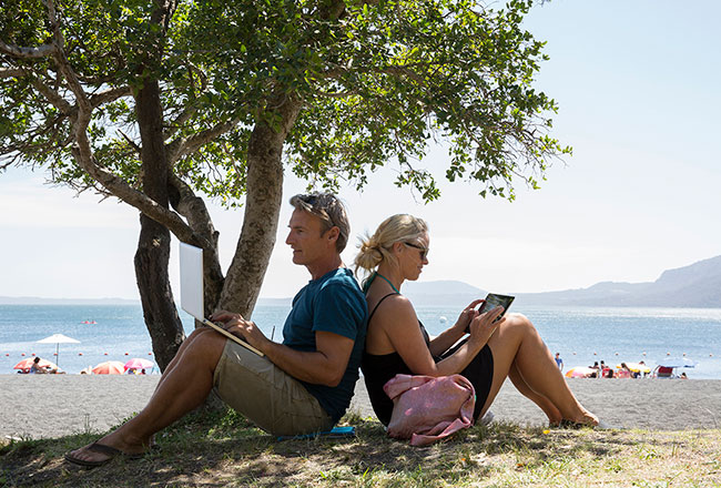 A couple sitting in the shade of a tree on a sunny day