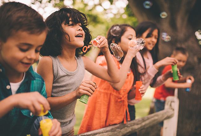 Group of children outside, blowing bubbles