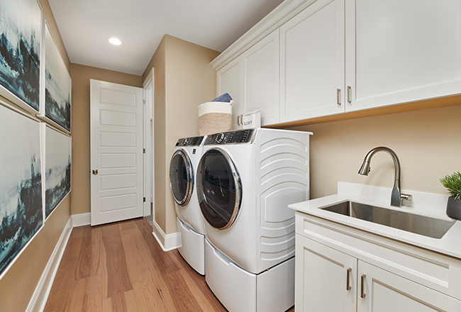 Laundry room with a white washer and dryer, built-in cabinets and a stainless-steel sink
