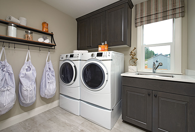 Washer and dryer with cabinets above, next to window with sink and cabinets below.