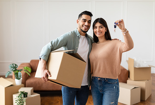 Young couple smiling and holding house keys and boxes