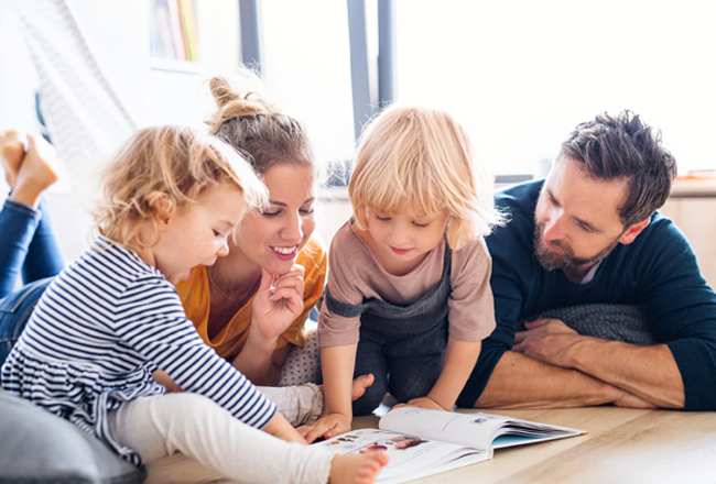 Parents reading a kids book about moving away to two young children