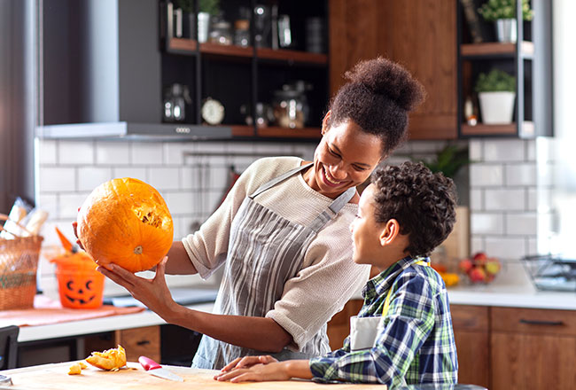 Mother & son carving a Halloween pumpkin.