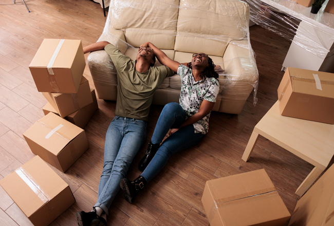 Man and woman laugh and relax on floor while moving into new home