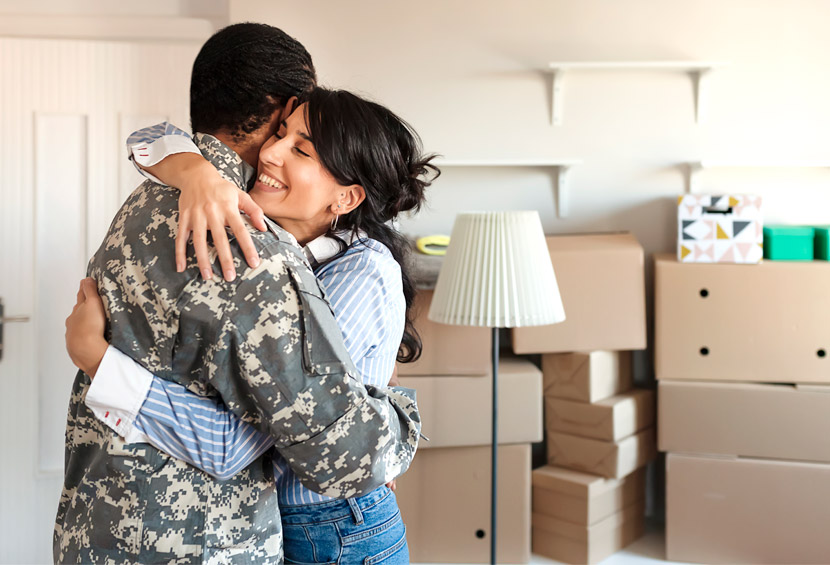 Military homebuyers hugging in front of moving boxes