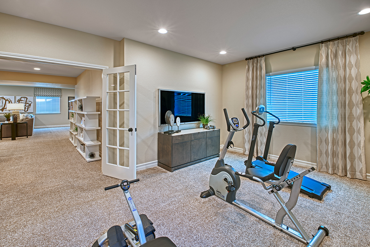Airy home gym with cardio machines and a TV