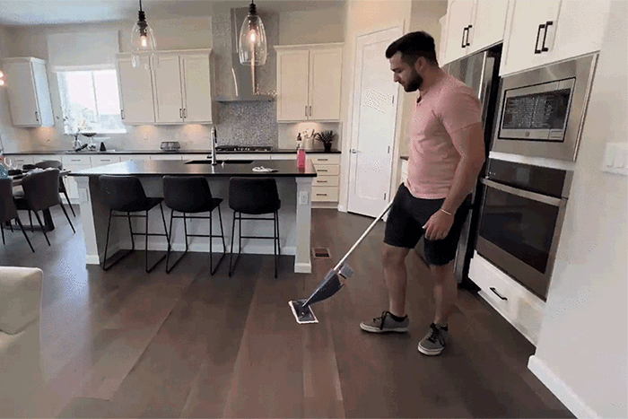 Man mopping the floor in a well-appointed kitchen