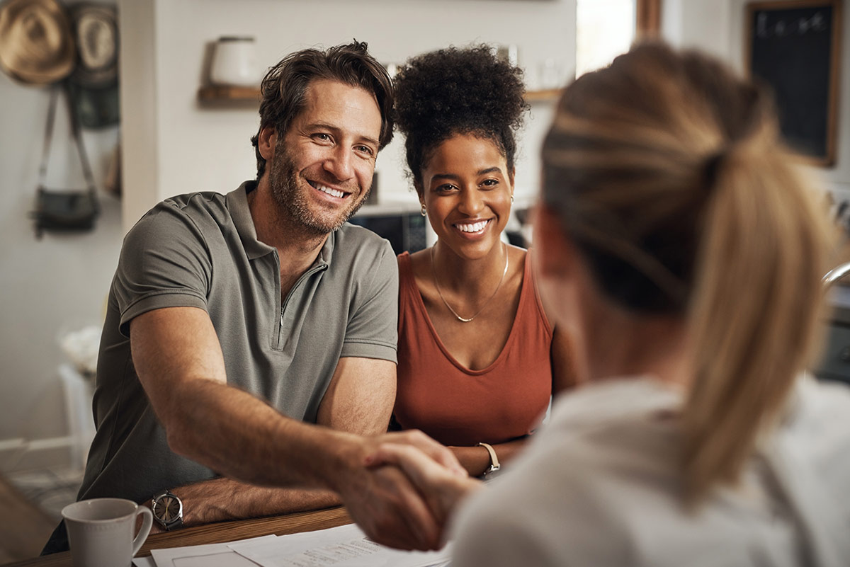 Couple shaking hands with mortgage broker after signing paperwork