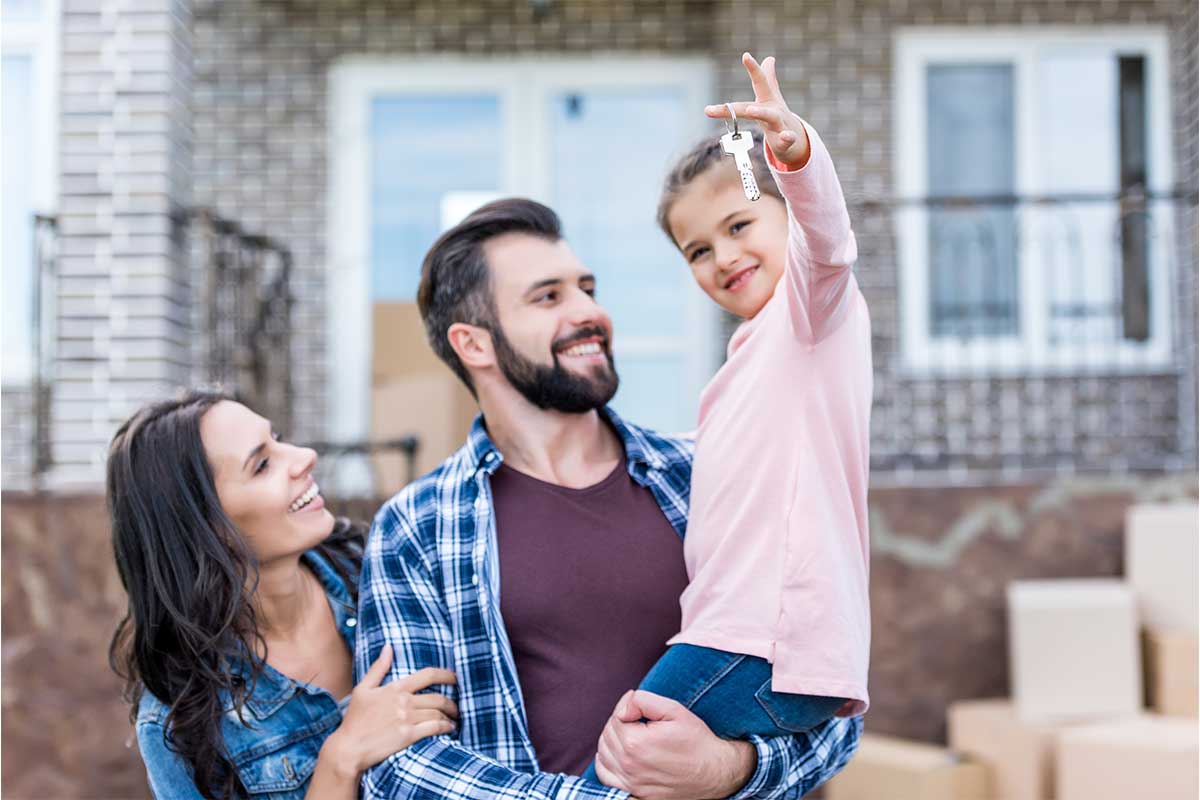 happy child holding up house keys while in her father's arms