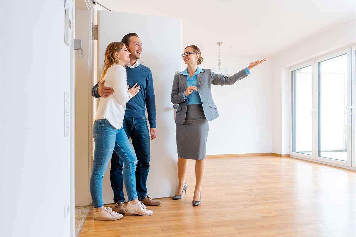 real estate agent showing a home to a young couple
