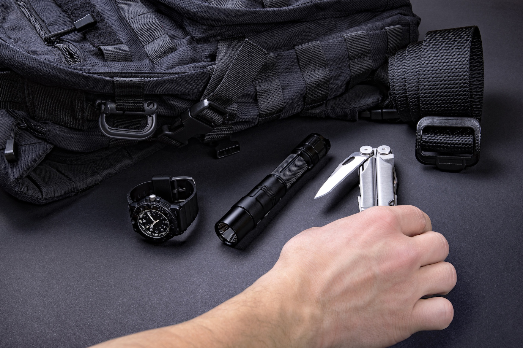 Man holding tools near a backpack