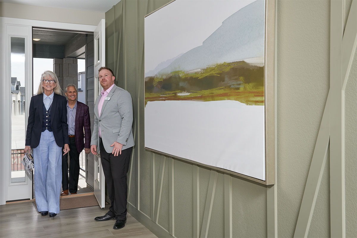 A sales associate leading two homebuyers into a model home