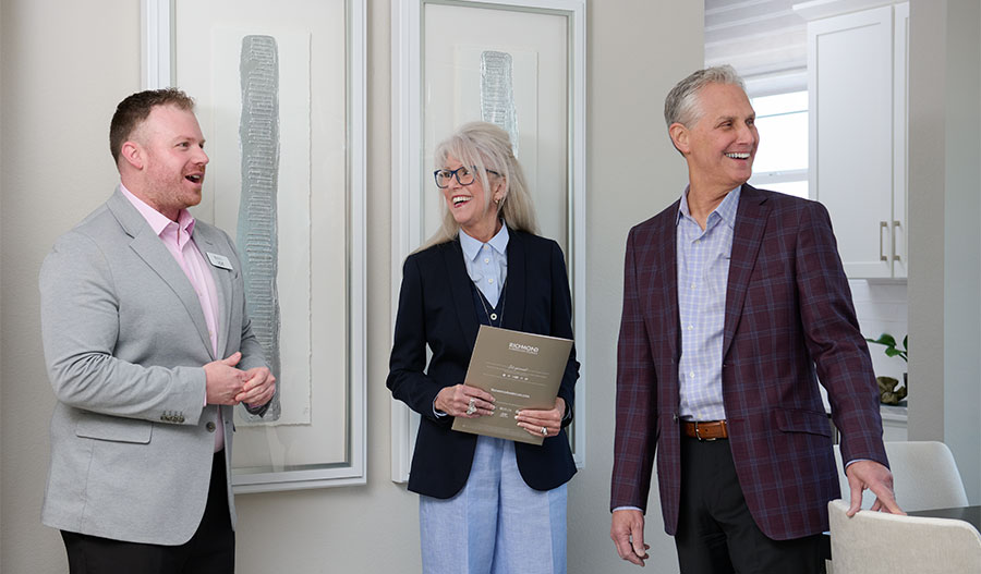 A homebuyer couple chatting with a Richmond American sales associate inside a model home