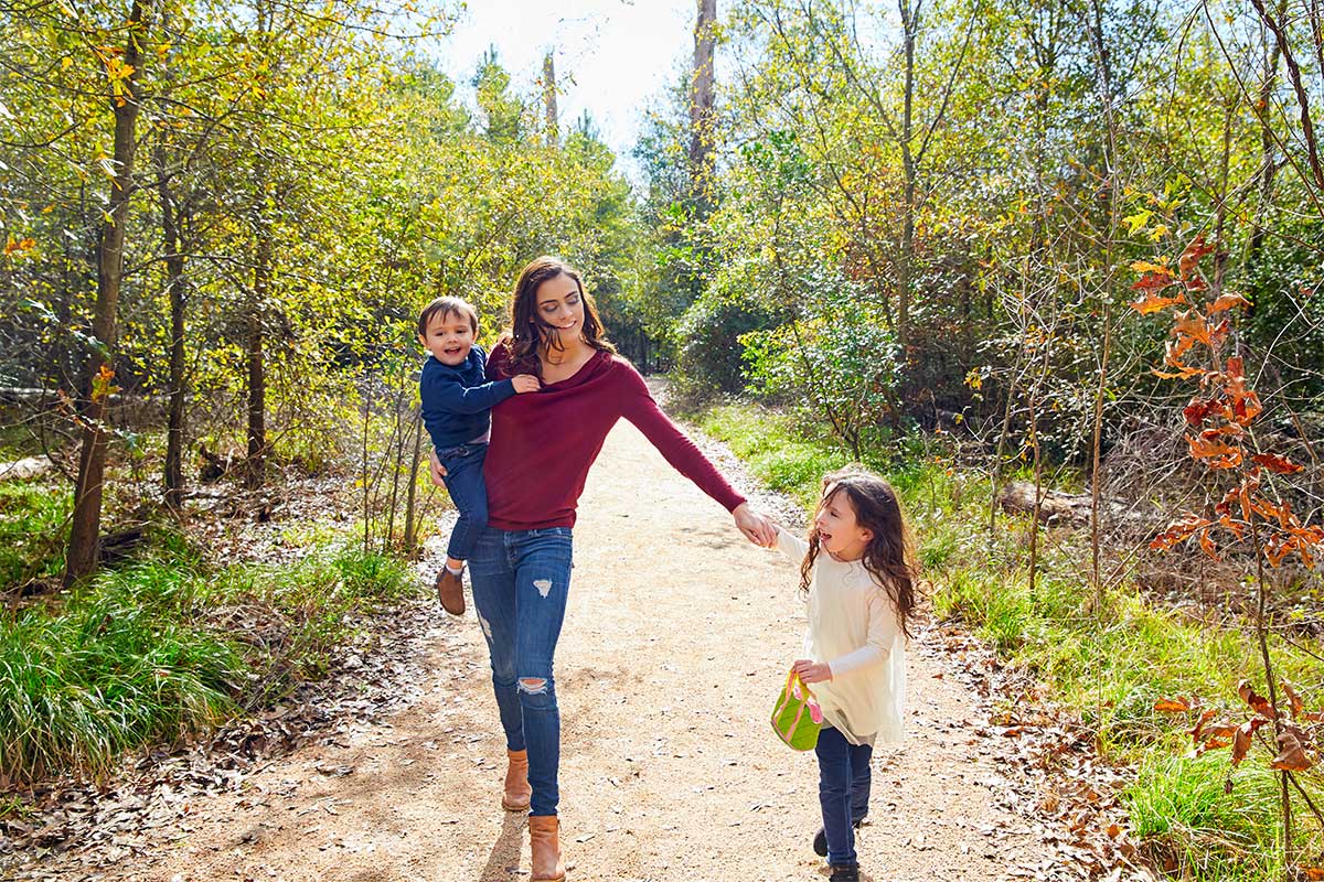 Young woman walking in a trail with two young children