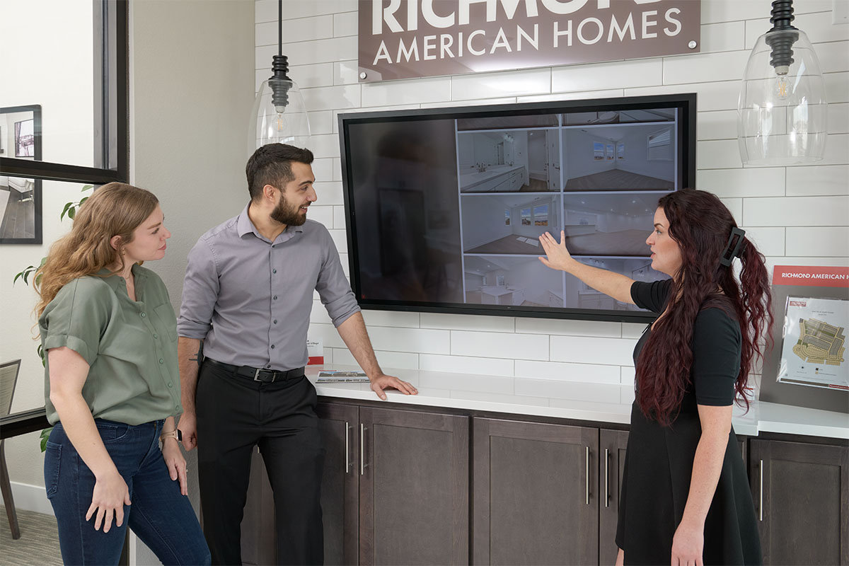 Man and two women viewing a floor plan on an interactive TV screen