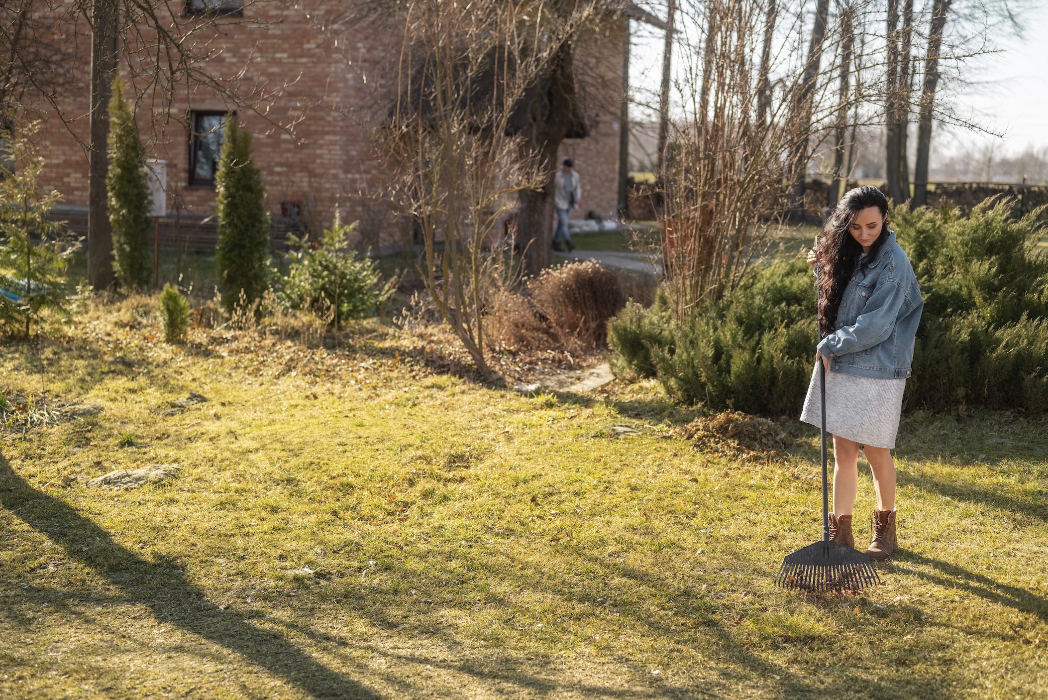 A woman raking leaves in her yard