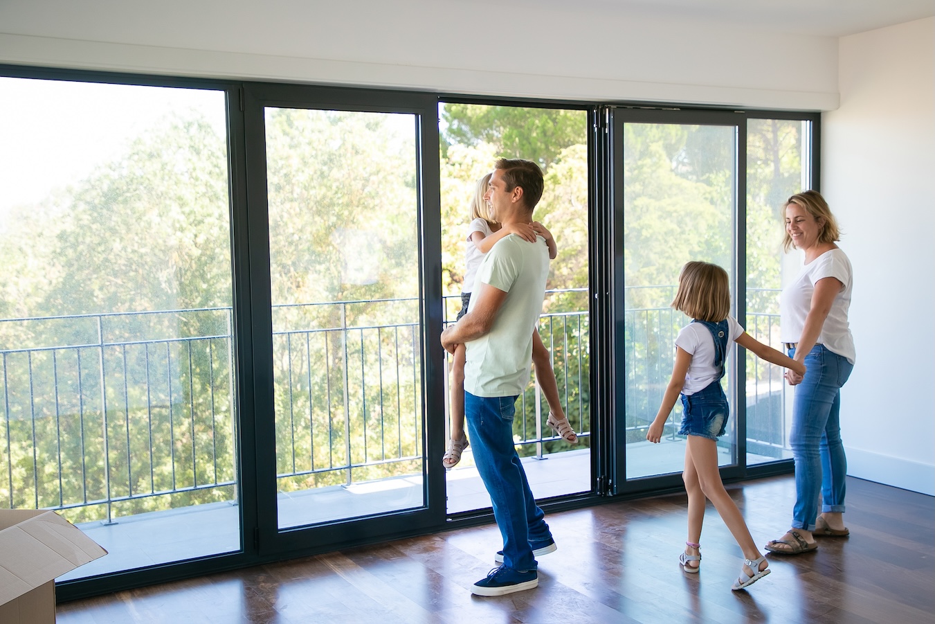 A couple and their two children looking out the windows in their new home