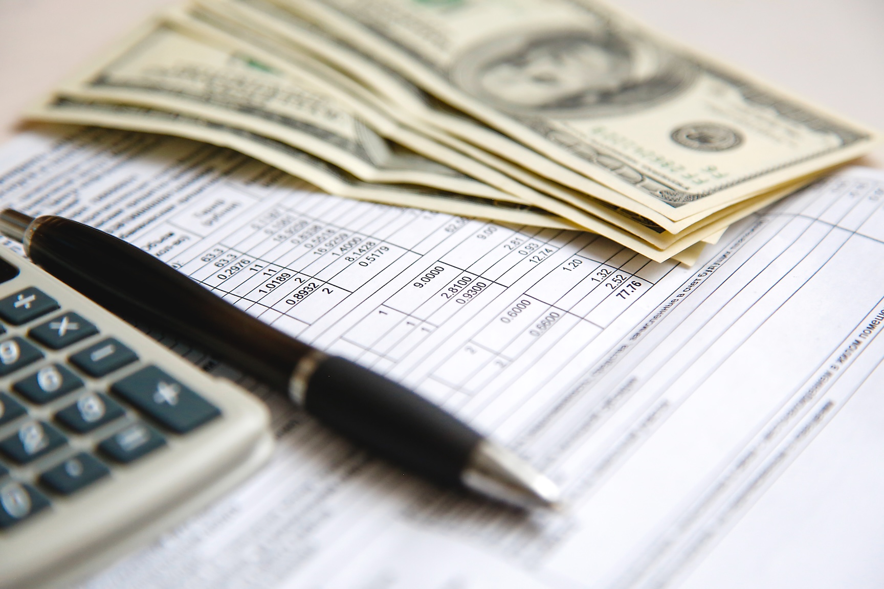 Cash on a table next to a bill and a calculator