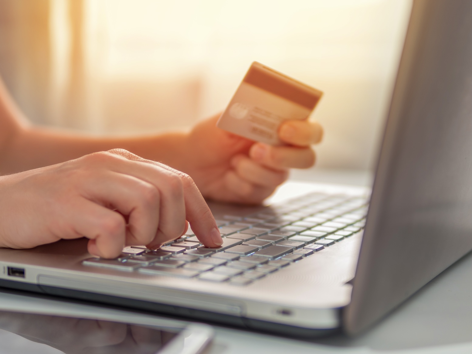 A person holding a credit card, paying a bill online