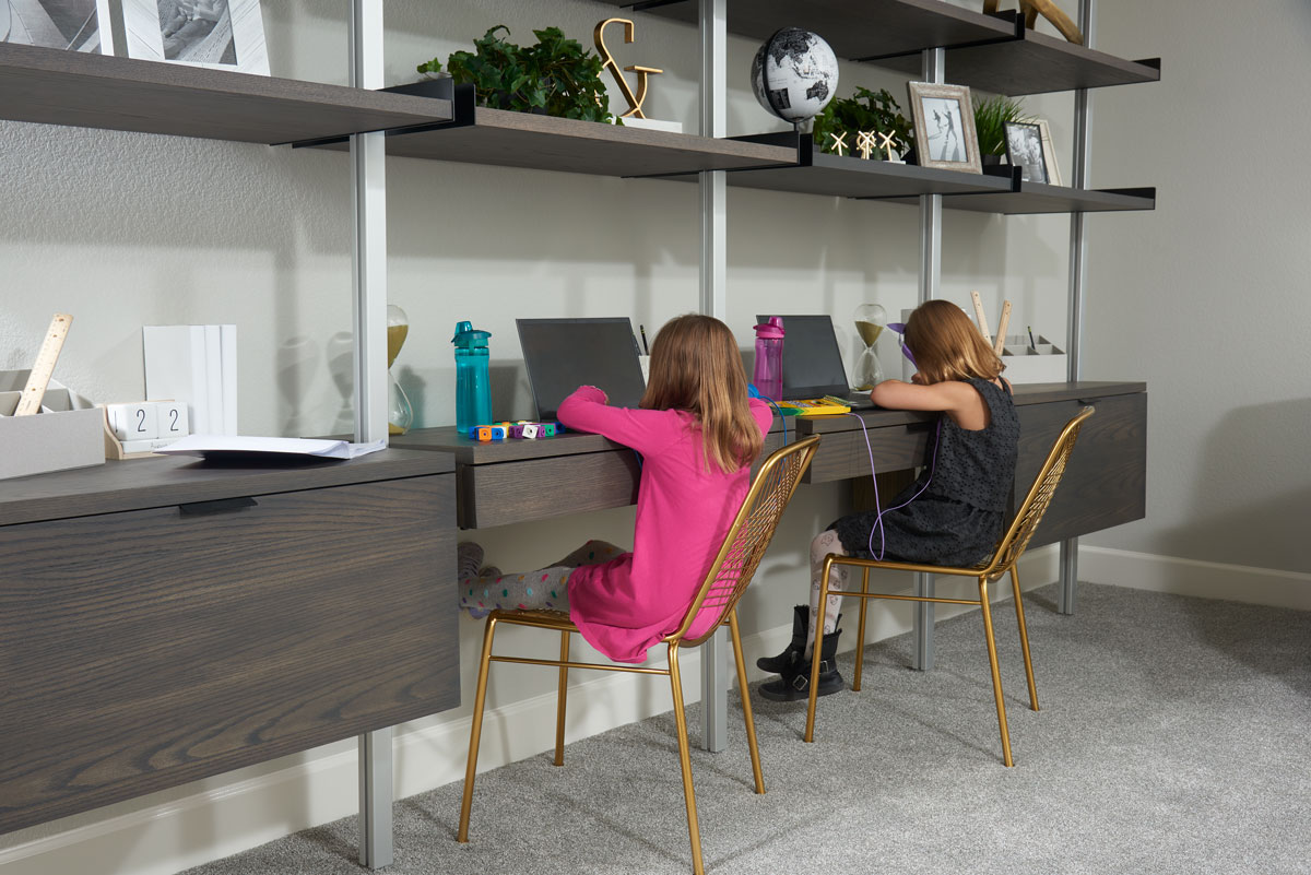 Two young kids sitting at a desk and working on homework in a loft space