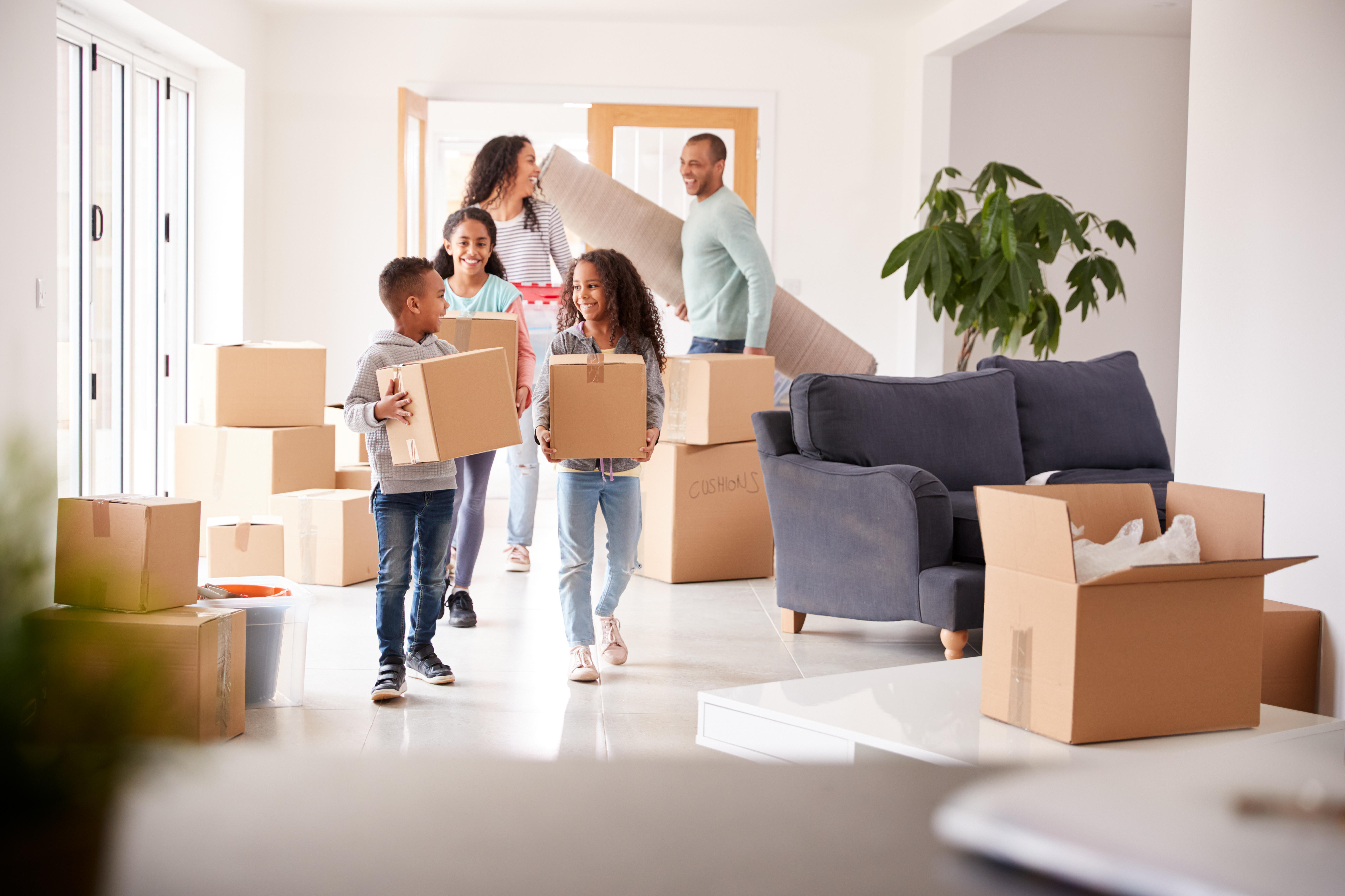 A young family walking into their new home with boxes in their hands