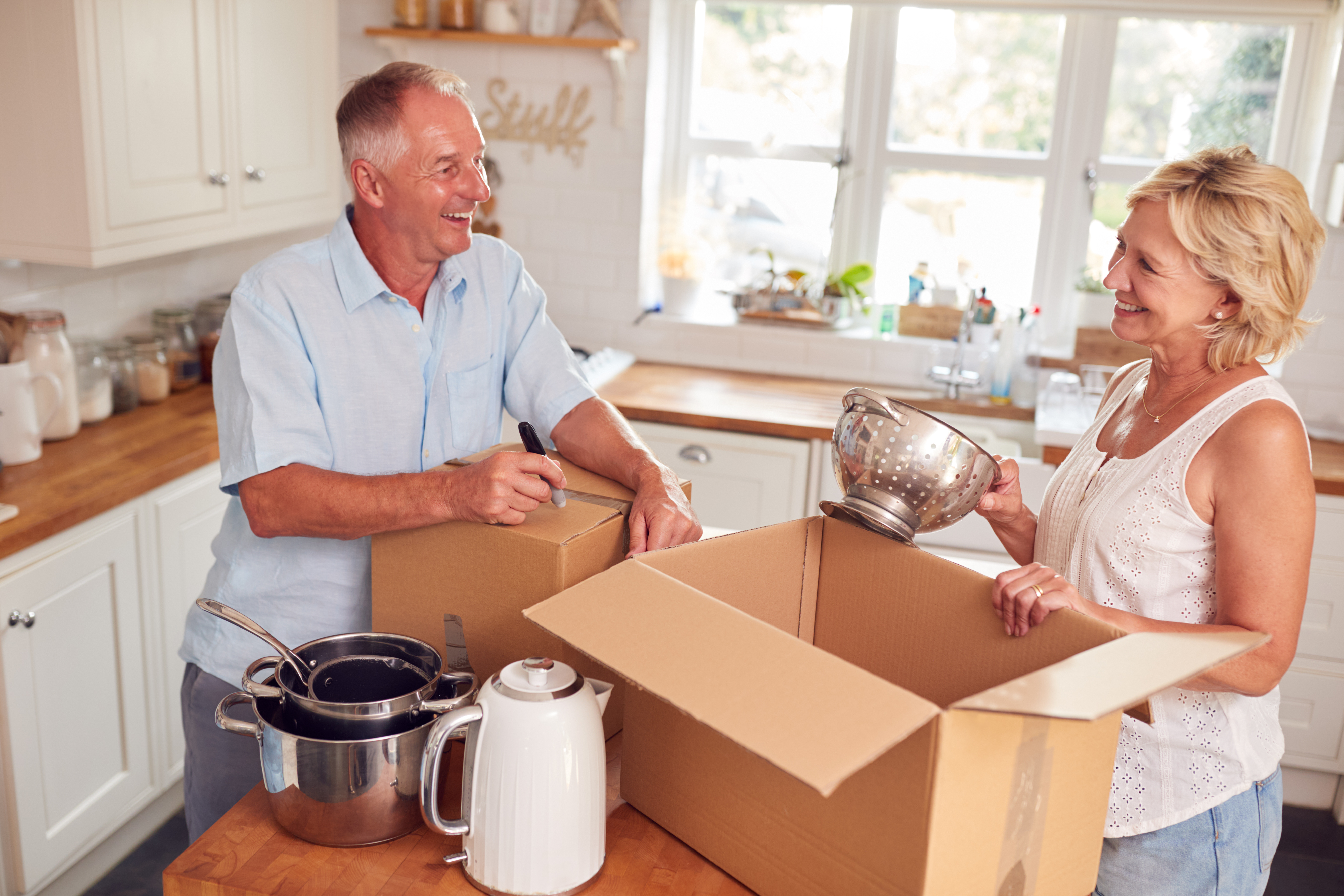 An older couple boxing up items in their kitchen