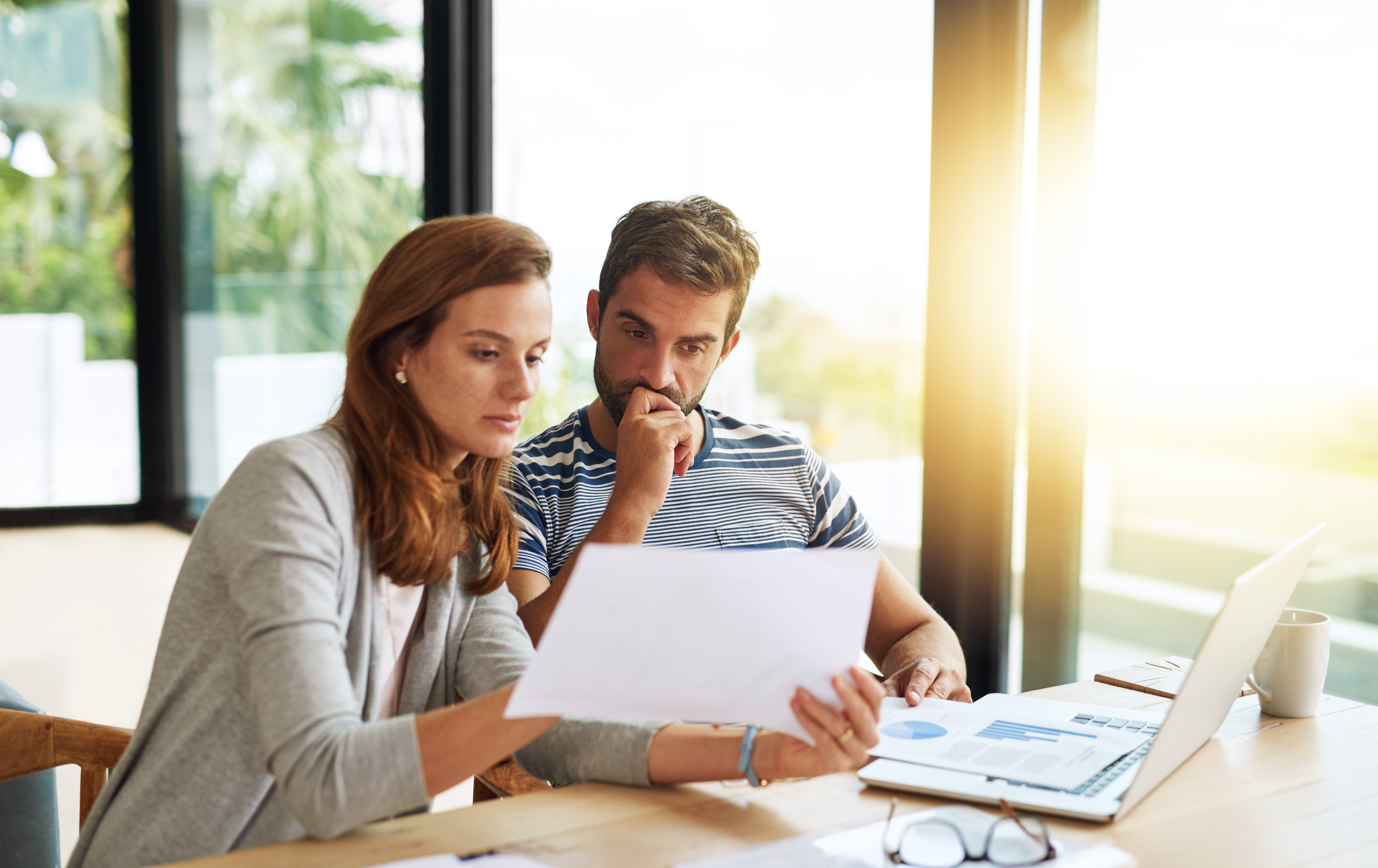 A couple sitting at a table, looking over financial paperwork