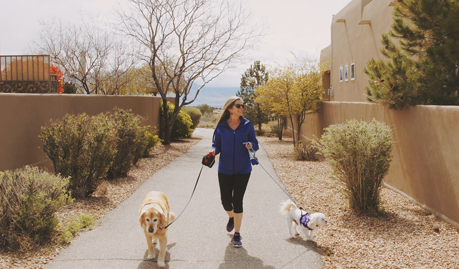 A woman walking two pups on a dog friendly neighborhood path