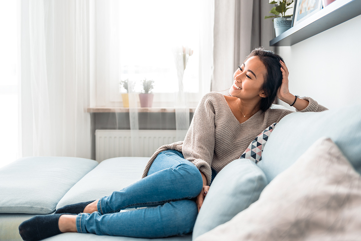 Smiling woman on a couch enjoying her smart home features
