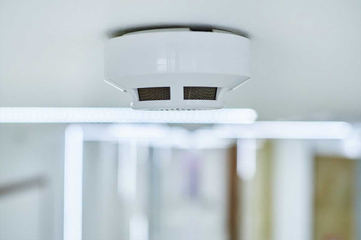 A smoke detector perched on a ceiling