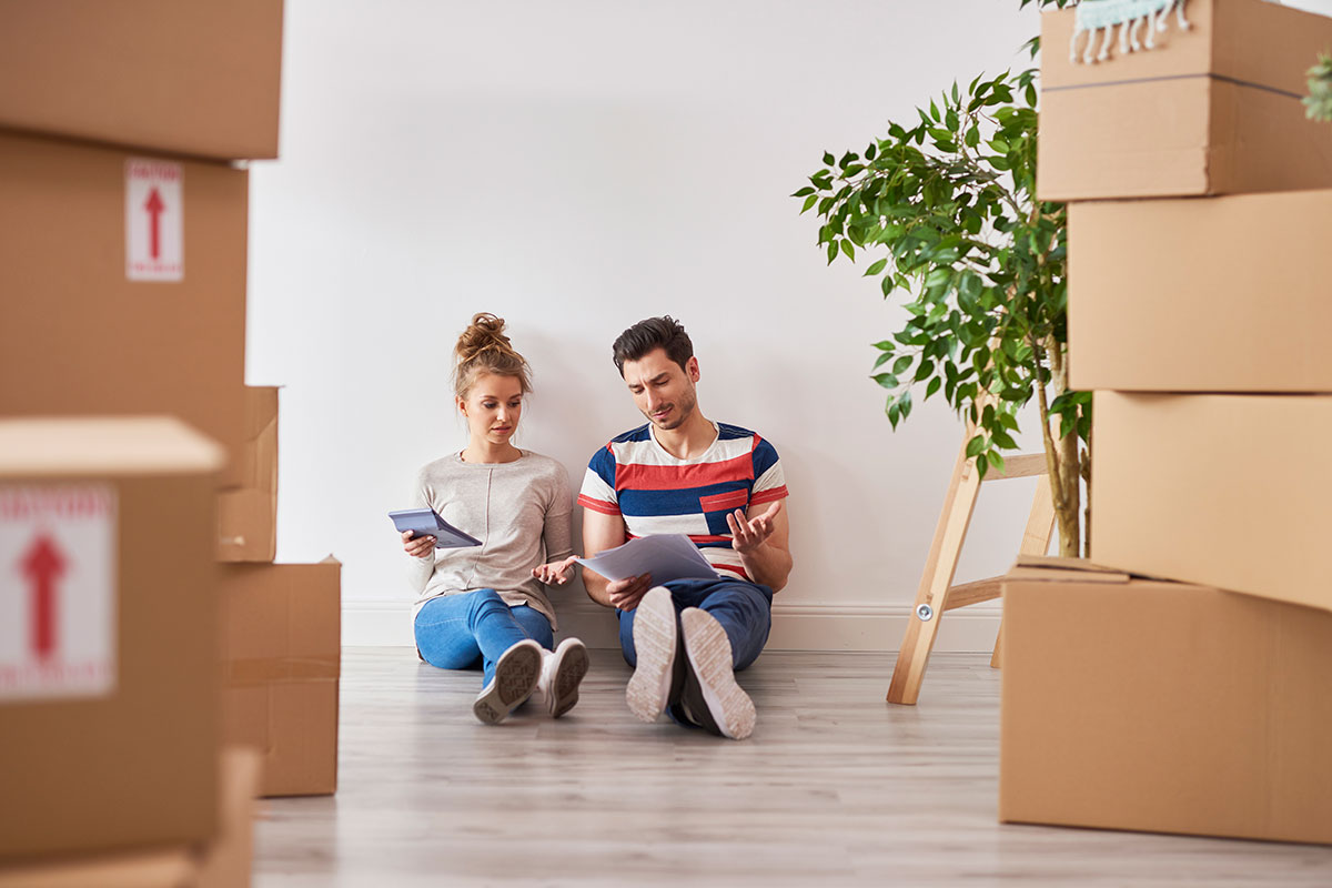 Worried Couple Examining Expenses Next To Moving Boxes