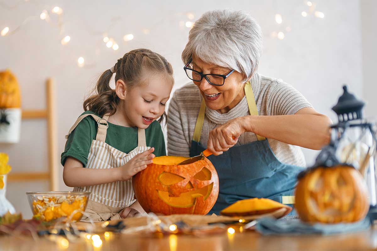 Elderly relative carving a pumpkin with a young girl