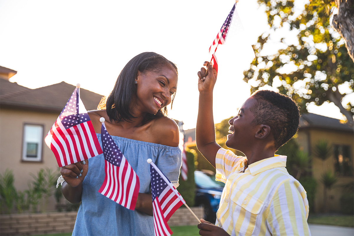 mother and son smiling, holding USA flags