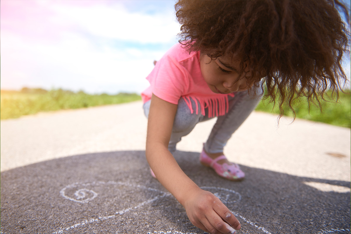 young girl drawing on the sidewalk with chalk