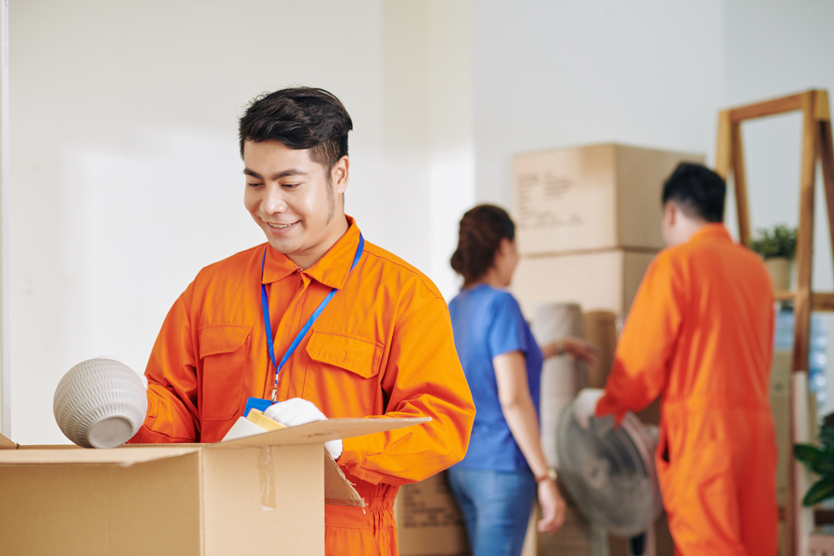 Smiling mover unpacking ceramic vases in new house of customer