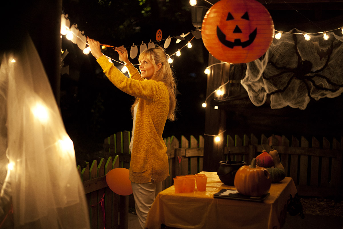 Woman in Halloween costume hanging outdoor lights