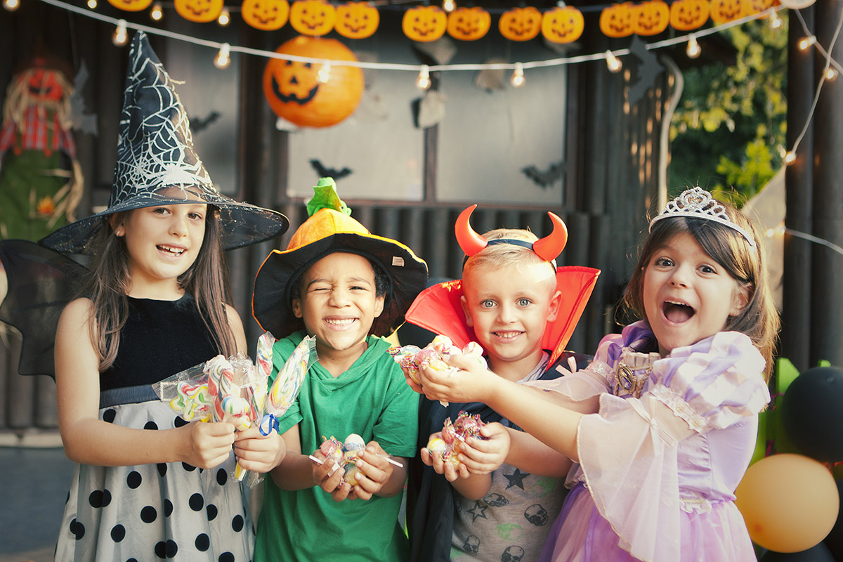 Children in Halloween costumes showing off candy
