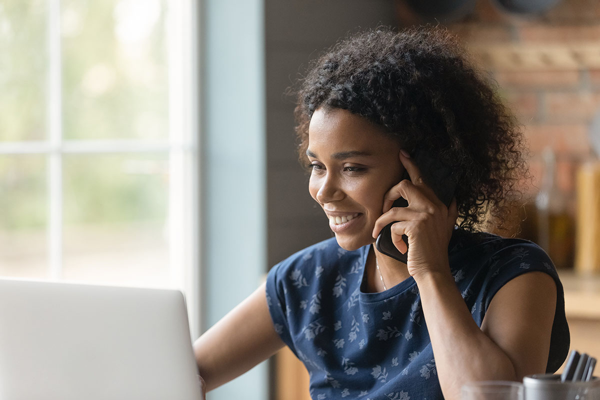 Woman holding phone to her ear looking at computer