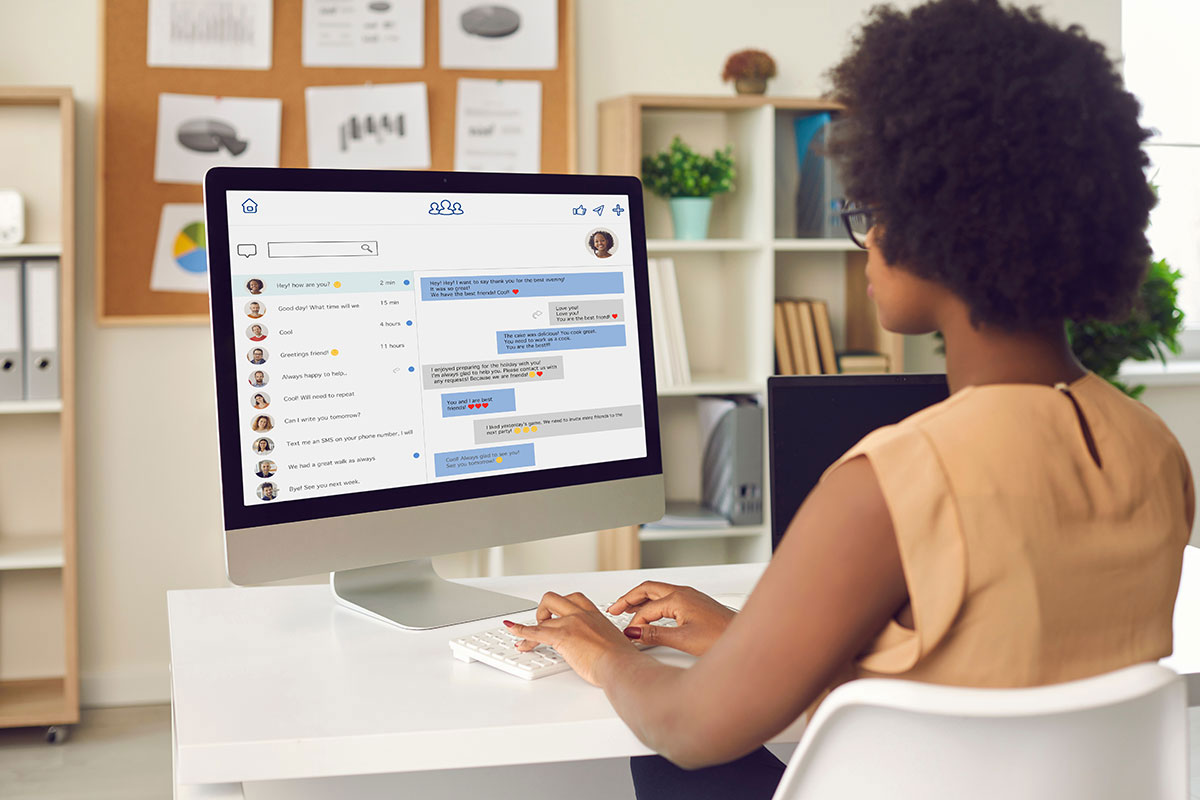 Woman sitting at desk typing on keyboard to message on her computer