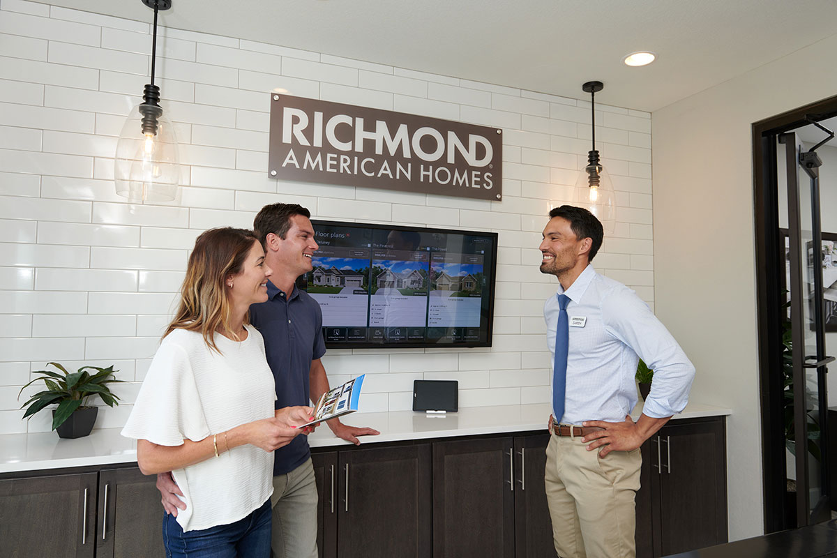 Real estate agent showing home with sliding doors to man and woman