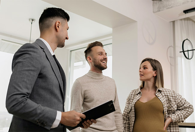Couple talks with real estate agent holding clipboard