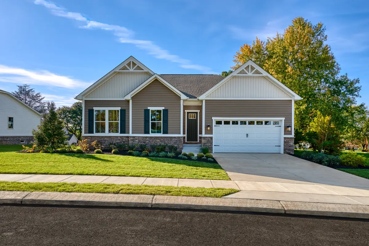 Single story home with two-car garage and large tree in the background