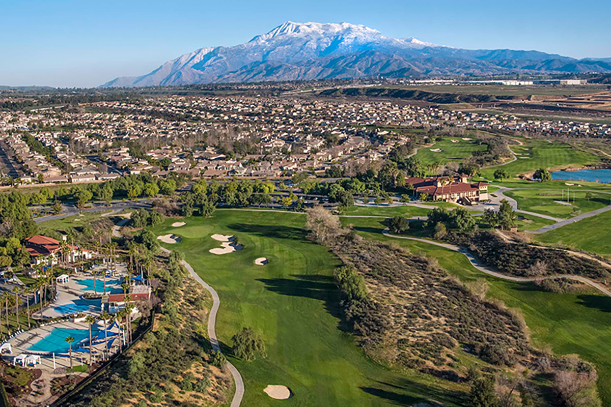 Aerial view of community of homes in Riverside California with golf course, mountains and pools