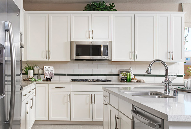 Kitchen with gas stove, large island, white brick backsplash and white cabinets