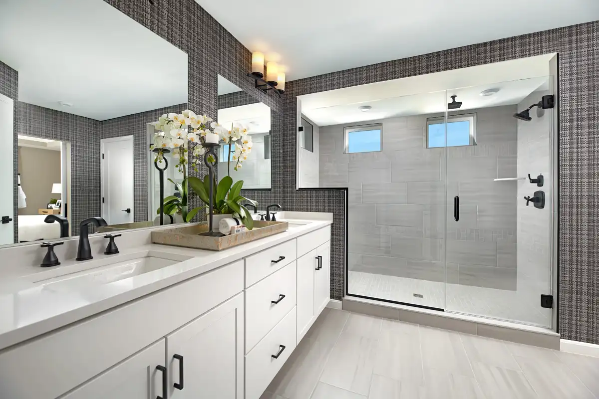 Bathroom with light double sink vanity with black hardware and step up to large shower stall with two small windows