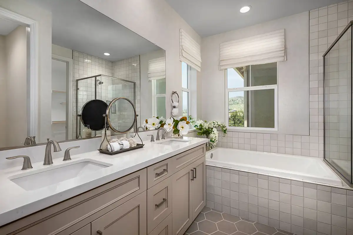 Two-sink vanity next to bathtub in the corner with a window on each wall