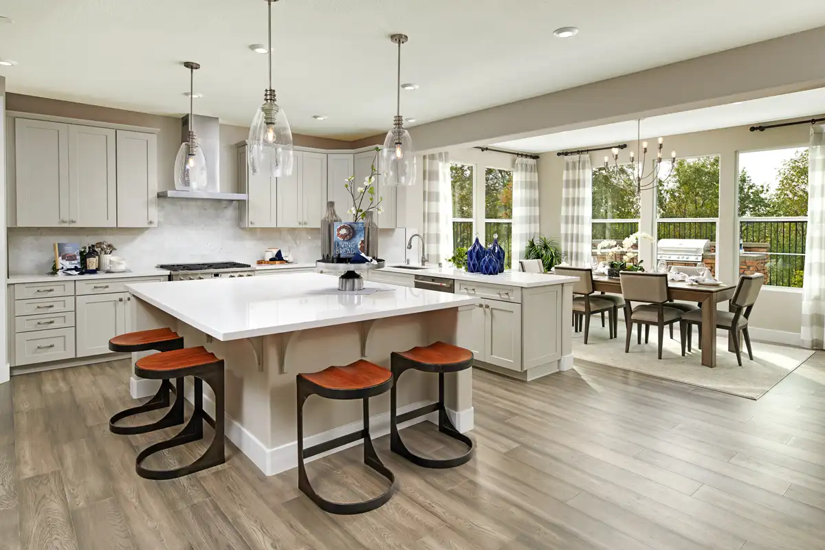 Kitchen with large island next to dining room surrounded by windows