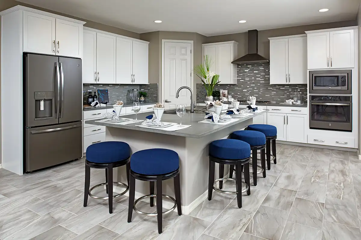 Kitchen with large island with five stools around it, gray backsplash, and one oven