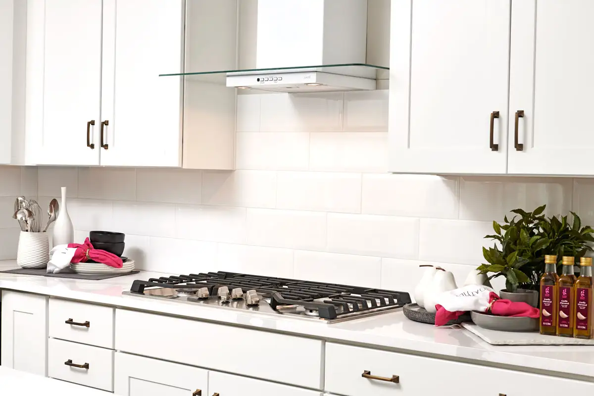 Gas stove with large brick-patterned backsplash and white cabinets