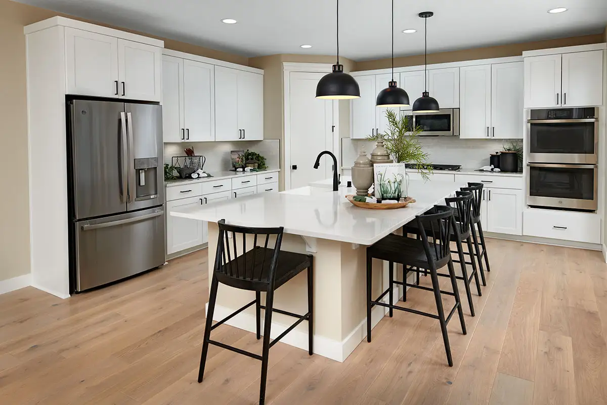 Kitchen with white cabinets and countertops and black ahrdware, with pantry and double oven